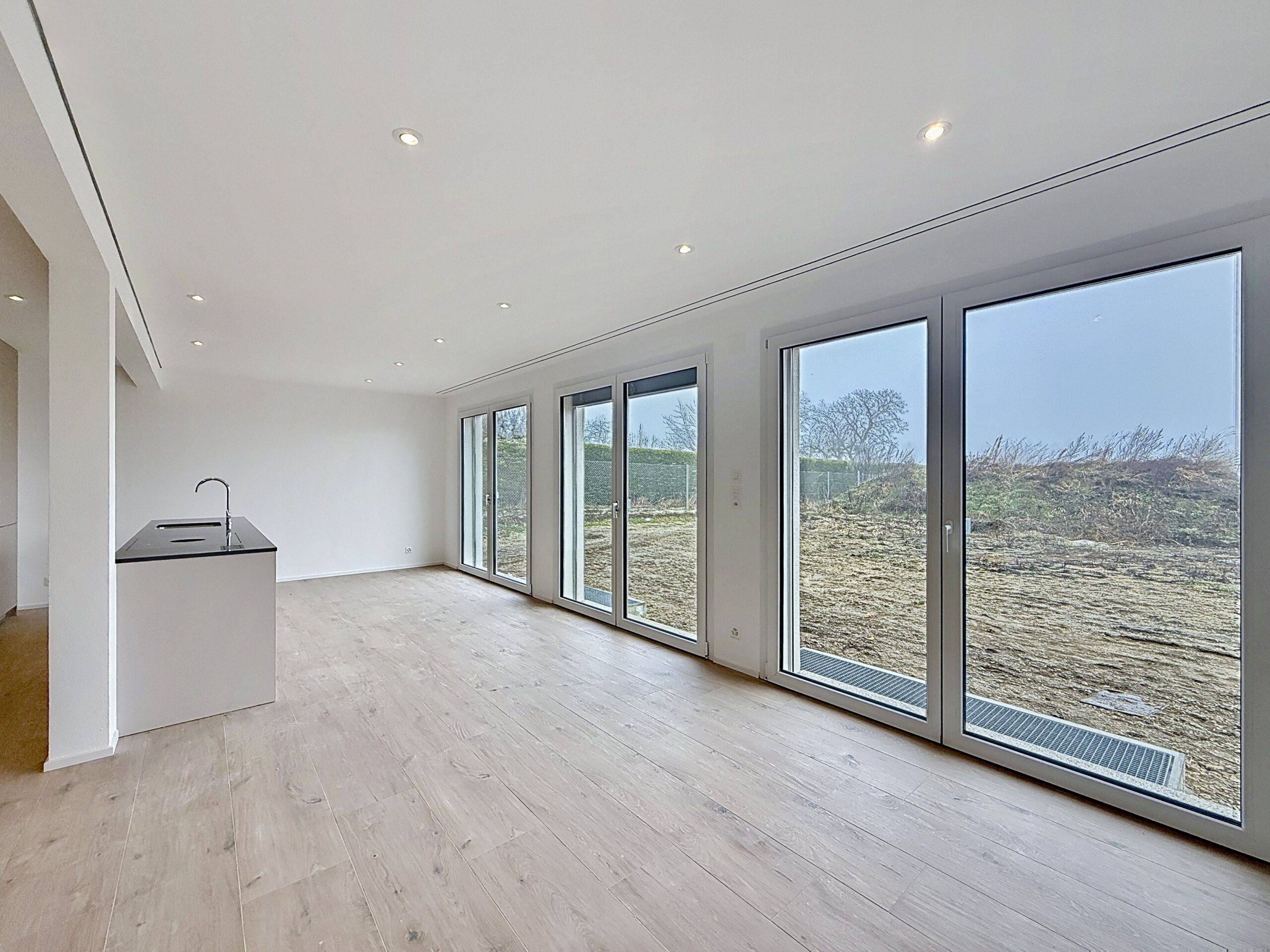 Salon lumineux avec grandes baies vitrées dans une villa moderne à Peney réalisée par LEGATO EG entreprise générale de construction